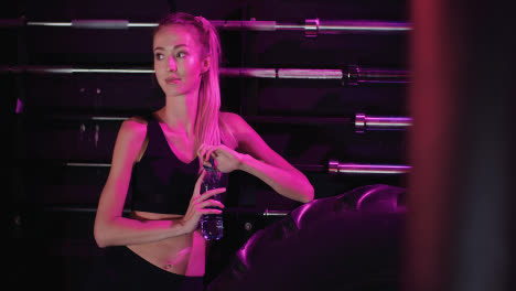 Smiling-Confident-Slim-Female-Athlete-Drinking-Water-From-Bottle-At-Fitness-Club